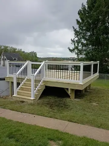 Elevated deck with white railings by KMA Carpentry